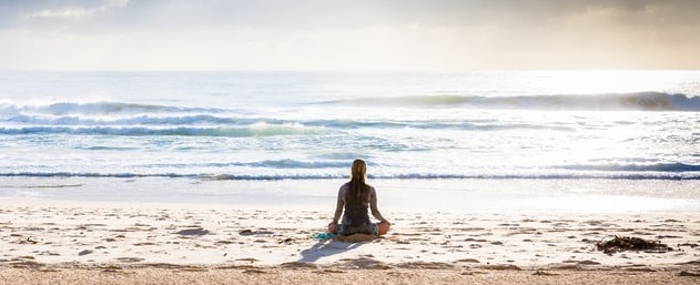 Photo of a person meditating on a quiet beach